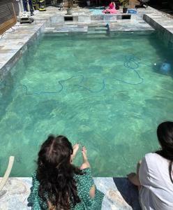 twee meisjes zitten voor een zwembad bij L'Hématite in Les Épesses