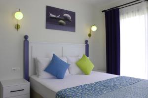 a bedroom with a bed with blue and green pillows at Cemile Hanım Konağı in Çeşme