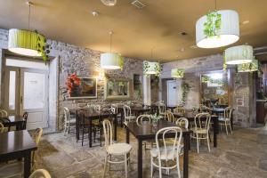 Un restaurante con mesas y sillas y una pared de piedra. en Hotel Alda Avenida, en Santiago de Compostela