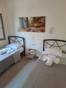 ein Schlafzimmer mit zwei Betten und einem Gemälde an der Wand in der Unterkunft Diolkos 2 in Nea Roda