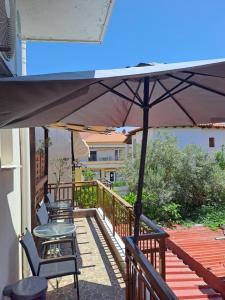 eine Terrasse mit Stühlen und einem Sonnenschirm auf einem Deck in der Unterkunft Diolkos 2 in Nea Roda