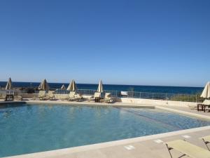 a swimming pool with chairs and the ocean in the background at Blue Beach Villas Apartments in Stavros