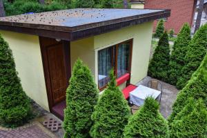 a small house with a red chair in a garden at Domek Campingowy Żółty in Pogorzelica