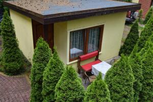 a small house with a red chair in a garden at Domek Campingowy Żółty in Pogorzelica