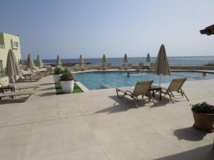 a swimming pool with lounge chairs and umbrellas at Blue Beach Villas Apartments in Stavros