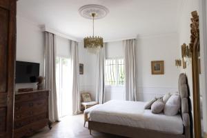 a bedroom with a bed and a television and a chandelier at Beach front Villa Cap D'Antibes in Antibes +74 photos