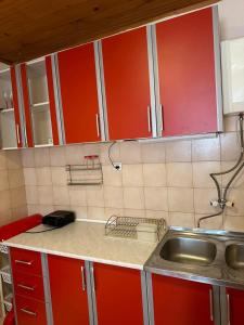 a kitchen with red cabinets and a sink at Apartmani VV in Cetinje