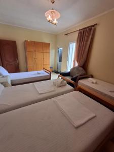 a hotel room with three beds and a chair at GuestHouseMantho in Gjirokastër