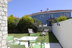 a patio with tables and chairs and a blue house at Cemile Hanım Konağı in Çeşme