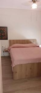 a bedroom with a wooden bed with a pink bedspread at beach apartment in Pefkohori