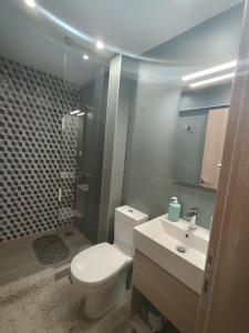a bathroom with a white toilet and a sink at beach apartment in Pefkohori