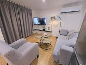 a living room with a couch and chairs and a tv at 10 Angels in Christchurch