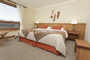 a bedroom with a large bed and a large window at Hotel Las Torres Patagonia in Torres del Paine
