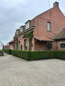 a brick house with a hedge in front of it at Lucilles in Heuvelland +12 photos