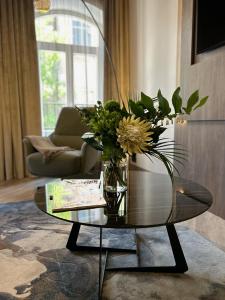 a vase of flowers on a glass table in a living room at CONTI HOTEL VILNIUS, Conference Centre, Restaurant & Bar in Vilnius +90 photos