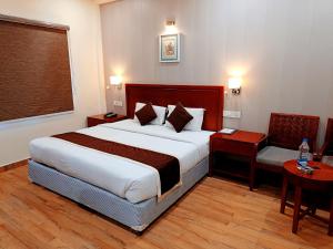a hotel room with a large bed and a chair at The Ved Mantra in Gwalior +14 photos