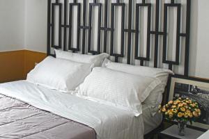 een bed met een zwart-wit hoofdeinde en witte kussens bij Hotel Antigone in Tirana