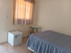 a bedroom with a bed and a window and a table at Hospedaria genivaldo in Santo Amaro