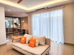 a living room with a couch with two orange pillows at Ayera Residence Muji X Near Permas X Staycation 4BR4B #12 pax by Cowidea in Masai