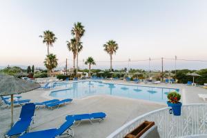 a swimming pool with blue chairs and palm trees at Pirgali Stone house in Ampavris
