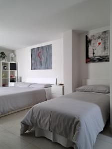 a white bedroom with two beds and a painting at Casa Margherita in Noci