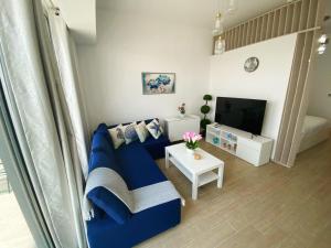 a living room with a blue couch and a tv at Yas Island Mayan 2 Junior 1 Bed Apartment by Central Stay in Abu Dhabi
