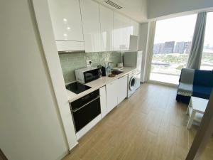 a kitchen with white cabinets and a stove top oven at Yas Island Mayan 2 Junior 1 Bed Apartment by Central Stay in Abu Dhabi