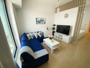 a living room with a blue couch and a tv at Yas Island Mayan 2 Junior 1 Bed Apartment by Central Stay in Abu Dhabi