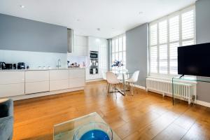 a large white kitchen with a table and a tv at Welcome London - Drury Lane in London