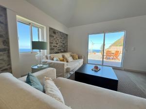a living room with two couches and a view of the ocean at Refúgio do Ilhéu in Porto Moniz