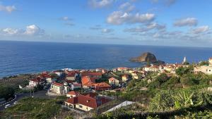 a small town on a hill next to the ocean at Refúgio do Ilhéu in Porto Moniz