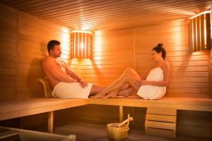 a man and woman sitting in a sauna at Hotel Kvarner - Liburnia in Opatija
