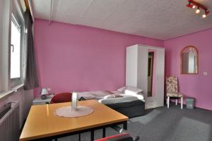 1 dormitorio con una pared de color rosa, 1 cama y 1 mesa en Monteurwohnung Steinsfeld Suhl, en Suhl