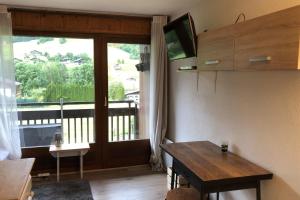 a living room with a table and a large window at Family studio near the slopes of Praz-sur-Arly in Praz-sur-Arly