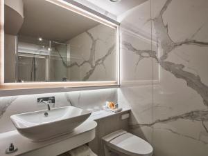 a bathroom with a sink and a toilet and a mirror at Club Quarters Hotel Covent Garden Holborn, London in London