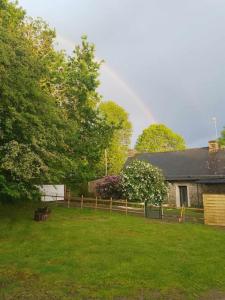 PloërdutNotre essentiel gîte en Bretagne的一道彩虹笼罩着一座有篱笆和房子的院子