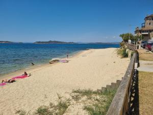 una playa con gente tirada en la arena y el agua en Villa Asteri Luxury Apartment Ouranoupoli, en Ouranoupoli