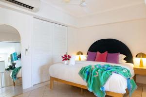 a bedroom with a large bed with colorful pillows at CASA PAPAYA Adults Only Apartment in Port Douglas