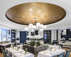 un comedor con mesas blancas y una lámpara de araña en Edouard 7 Paris Opéra, en París