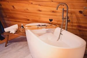 a bath tub with a faucet and a glass of wine at Black Chalet in Vartop
