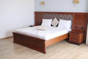a bedroom with a large wooden bed with white sheets at Hotel Restaurant Elite in Drobeta-Turnu Severin
