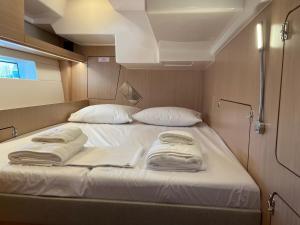 Una cama grande con sábanas blancas y almohadas en un barco. en Vela, en Volos