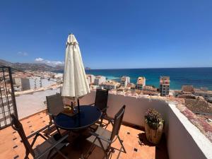 a balcony with a table and an umbrella and the ocean at Casa Asplund, casco antiguo con vistas al mar in Altea