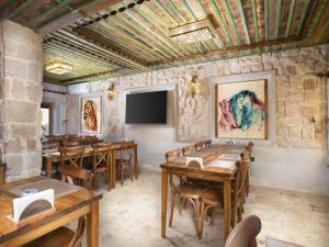 a restaurant with wooden tables and chairs and a flat screen tv at Rapsodi Cappadocia in Göreme