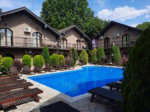 a swimming pool in front of a house with benches at Apartman Aleksa in Bela Crkva