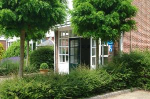 a house with a black and white door and trees at Fletcher Landgoedhotel Renesse in Renesse