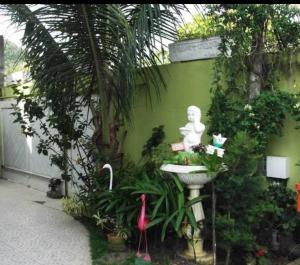 a green wall with a statue next to a sink at Suítes felicidade Rio Centro in Rio de Janeiro