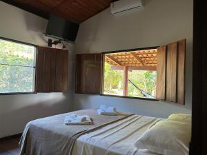 a bedroom with two towels on a bed with two windows at Pousada Rio das Almas in Pirenópolis +47 photos