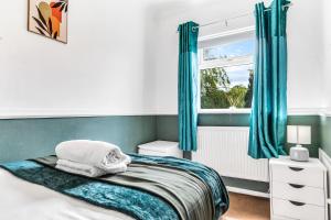 a bedroom with a bed with blue curtains and a window at Modern 2-Bed Home Walk to Ashby Town Centre in Ashby de la Zouch