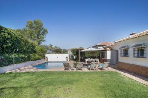 a backyard with a pool and chairs and a house at Casa Cerezo - Chalet Lujo in Casabermeja